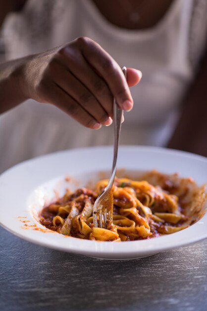 young beautiful African American woman enjoys while eating delicious pasta