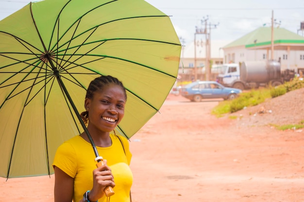 Young beautiful african lady using an umbrella to protect herself under a very sunny weather