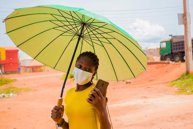 Young beautiful african lady wearing face mask preventing herself from the outbreak in the society feeling excited about what she saw on her smartphone