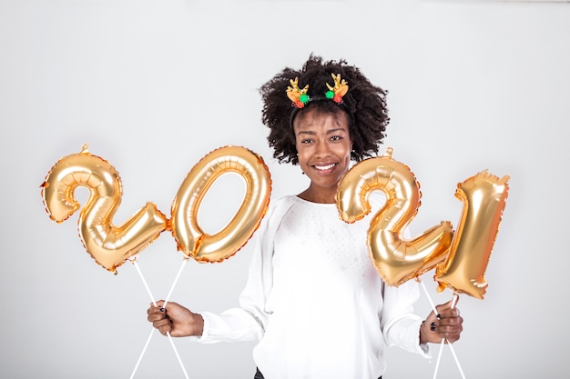 Young beautiful African with reindeer horns on her head holding balloons