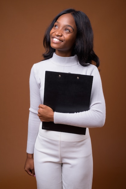 Young beautiful African Zulu businesswoman against brown background