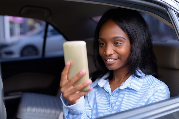 Young beautiful African Zulu businesswoman riding inside the car