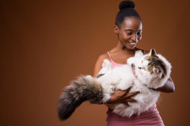 Young beautiful African Zulu woman holding cat while smiling