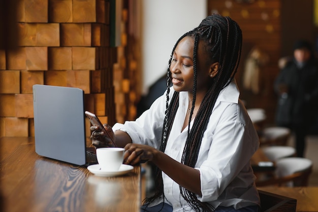 Young beautiful AfroAmerican businesswoman using laptop while working in cafe