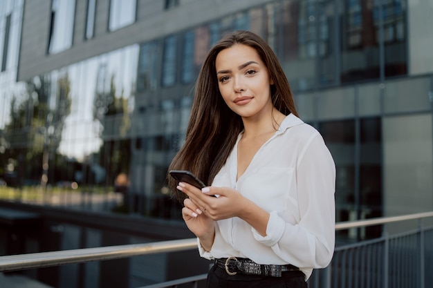 Young beautiful ambitious businesswoman boss company manager walks out in front of modern glass