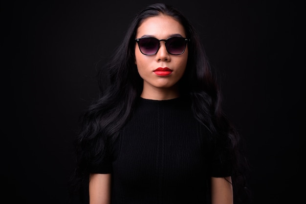 Photo young beautiful asian  businesswoman against black wall