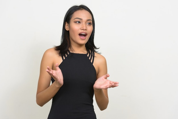 young beautiful asian businesswoman wearing dress against white wall
