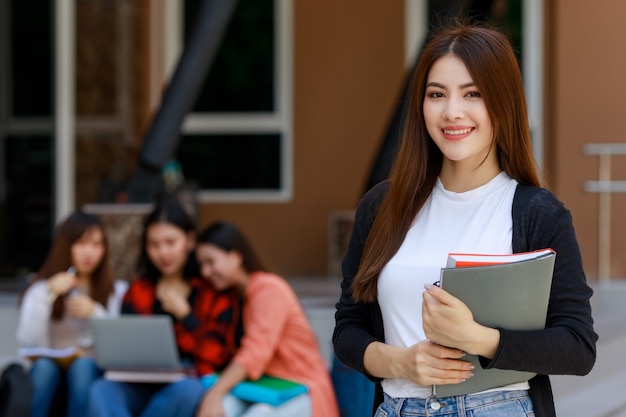 Young and beautiful Asian college student girls holding books