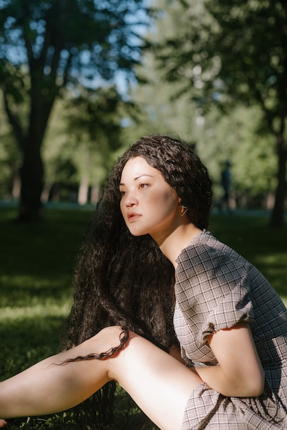 Young beautiful asian female sitting on the grass in a park