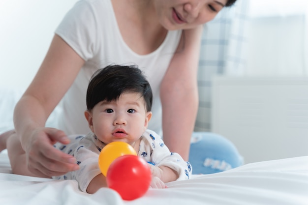 침대에 그녀의 작은 귀여운 아기와 함께 젊은 아름 다운 아시아 어머니.