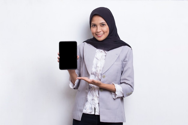 Young beautiful asian muslim woman demonstrating mobile cell phone isolated on white background