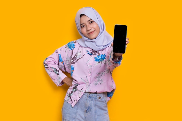 young beautiful asian muslim woman demonstrating mobile cell phone isolated on white background