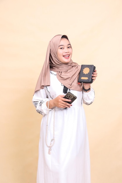 young beautiful Asian Muslim woman in hijab quran promotion laughing expression and holding prayer b