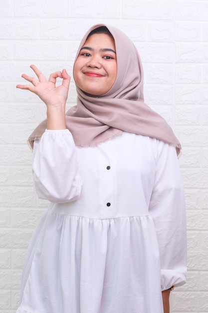 Young beautiful Asian muslim woman smiling while making okay sign