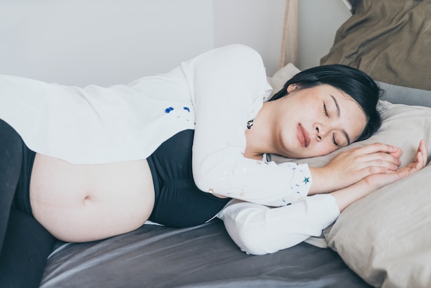Молодая красивая азиатских беременная женщина, спать на кровати