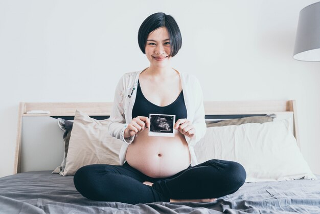 Young beautiful Asian pregnant woman with ultrasound film