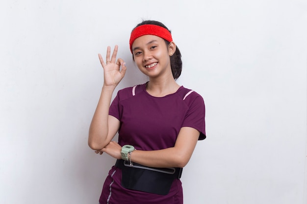 Young beautiful asian sporty woman showing a thumbs up ok gesture on white background