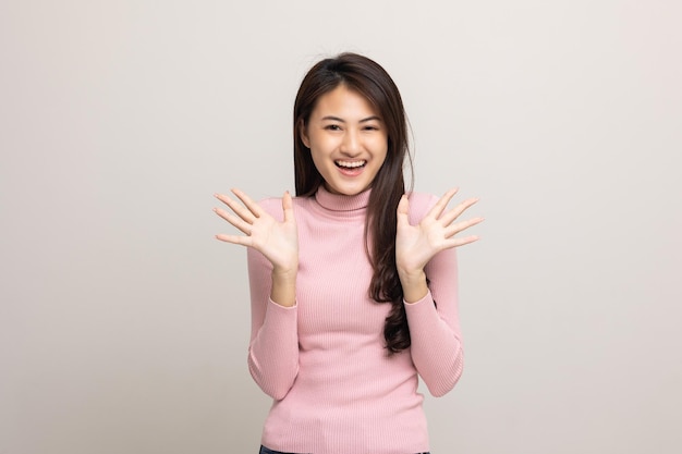 분홍색 셔츠를 입은 젊고 아름다운 아시아 10대 소녀가 고립된 흰색 배경에 서서 미소를 짓고 있습니다.