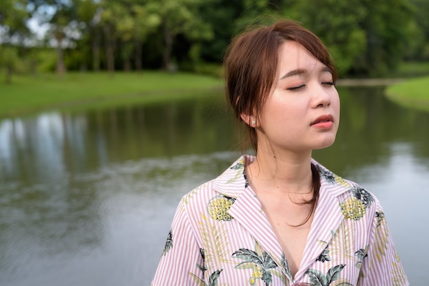 Young beautiful Asian tourist woman relaxing at the park