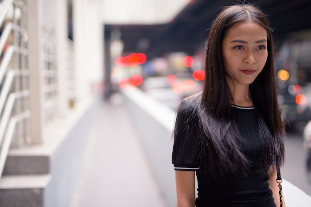 Young beautiful Asian tourist woman thinking in the city streets