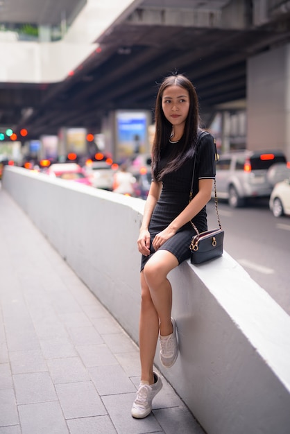 Young beautiful Asian tourist woman thinking in the city streets