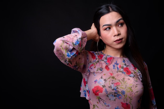 young beautiful Asian transgender woman against black