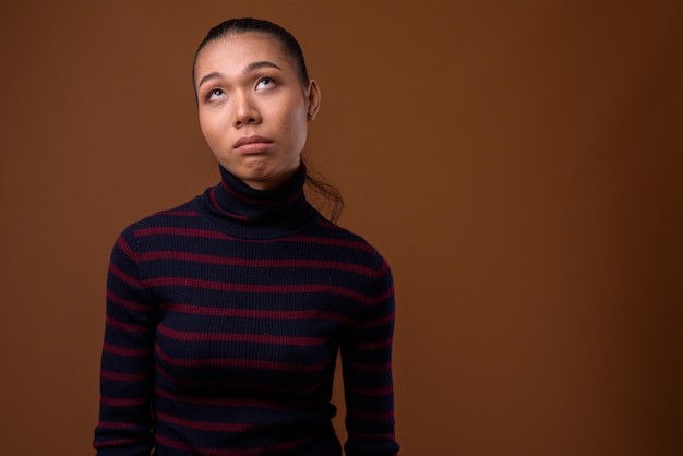 Photo young beautiful asian transgender woman against brown background