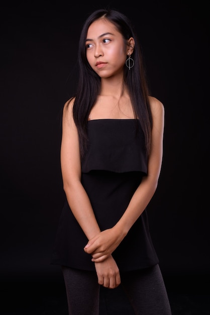  young beautiful Asian woman against black wall