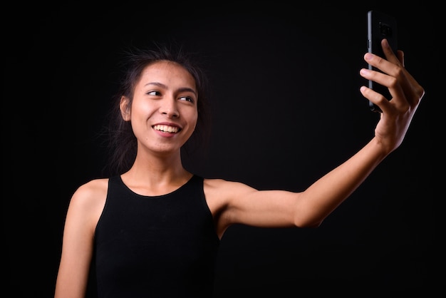  young beautiful Asian  woman against black wall