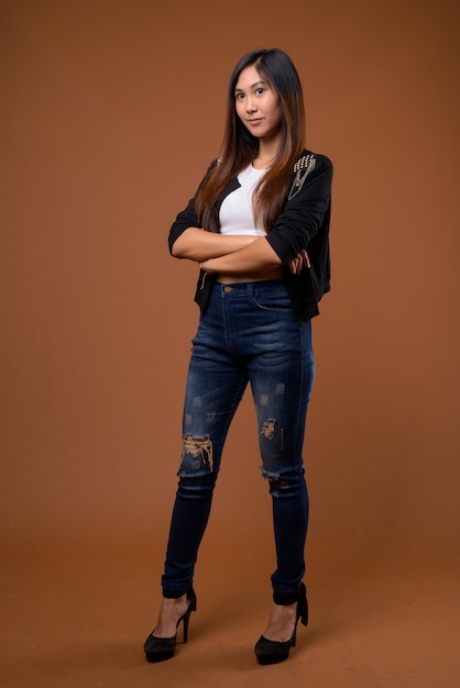 Young beautiful Asian woman against brown background