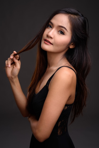 Young beautiful Asian woman against gray