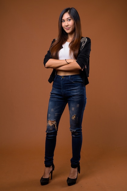 Young beautiful Asian woman on brown wall