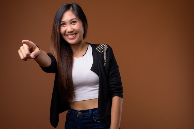 Young beautiful Asian woman on brown wall