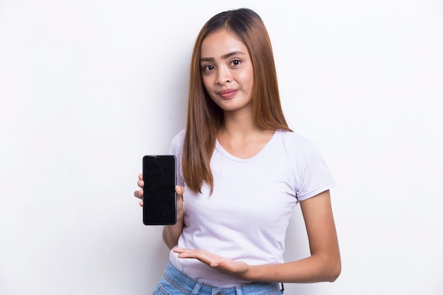 흰색 배경에 고립 된 휴대 전화를 보여주는 젊은 아름 다운 아시아 여자