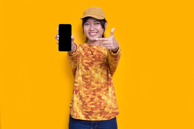 young beautiful asian woman demonstrating mobile cell phone isolated on yellow background