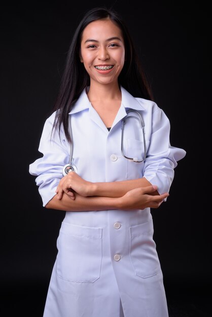  young beautiful Asian woman doctor against black wall