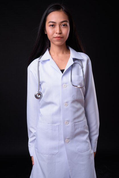  young beautiful Asian woman doctor against black wall