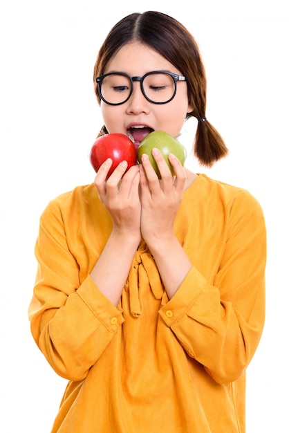 Giovane bella donna asiatica che mangia mela rossa e mela verde