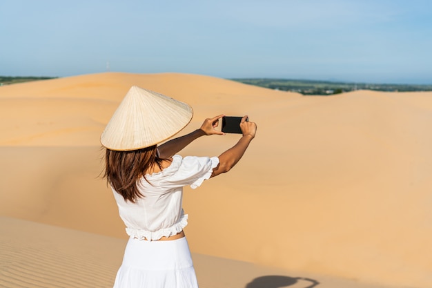 La giovane bella donna asiatica gode del momento nel deserto.