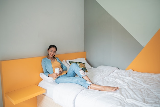 Young beautiful asian woman having coffee in cozy bedroom