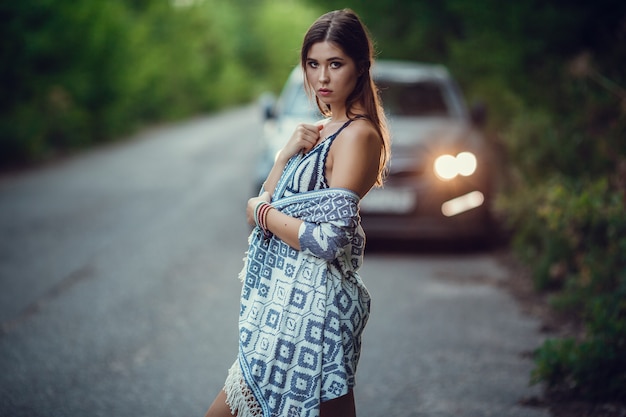 Young beautiful Asian woman in hippy style. travels by hitchhiking. Road in the mountains.