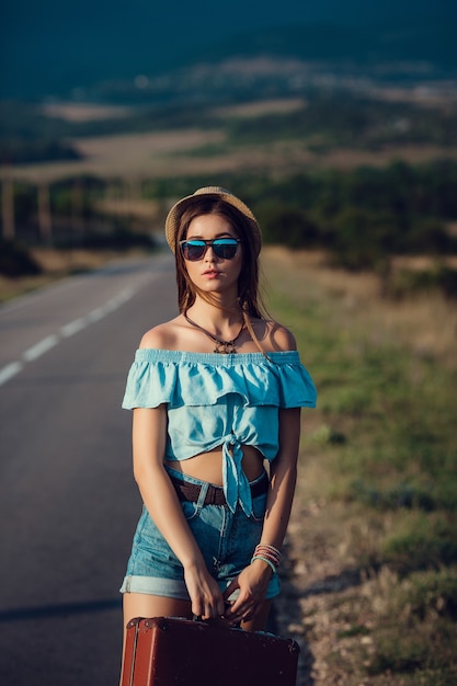 Young beautiful Asian woman in hippy style. travels by hitchhiking. Road in the mountains.
