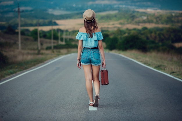 Young beautiful Asian woman in hippy style. travels by hitchhiking. Road in the mountains.