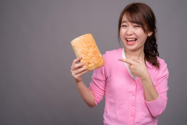 Giovane bella donna asiatica che tiene pezzo di pane