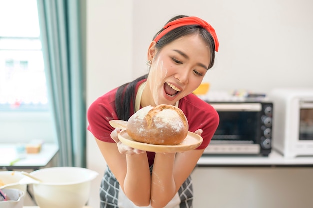 젊은 아름다운 아시아 여성이 부엌, 빵집, 커피숍 사업에서 베이킹을 하고 있습니다