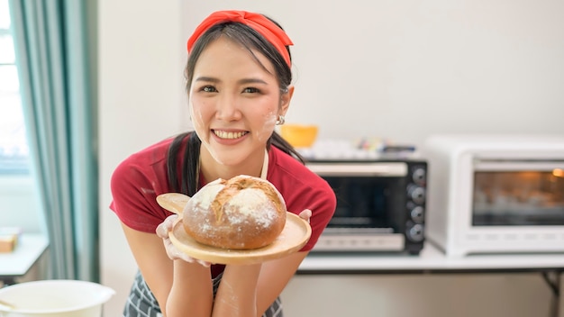 Una giovane bella donna asiatica sta cuocendo nella sua attività di cucina, panetteria e caffetteria