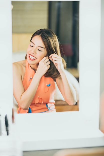 若い美しいアジアの女性メイクを鏡の近くに作る
