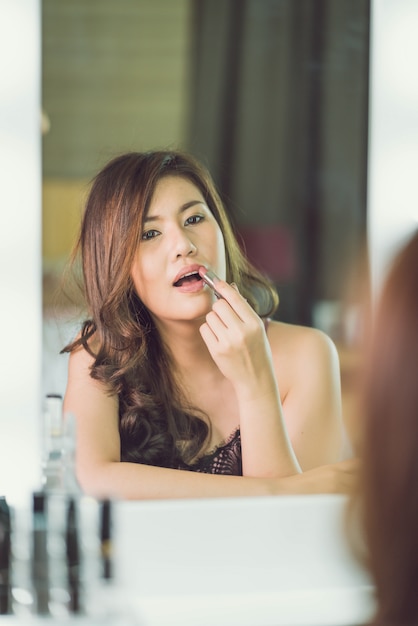 Young Beautiful Asian Woman making make-up near mirror