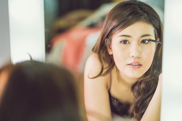 Young Beautiful Asian Woman making make-up near mirror