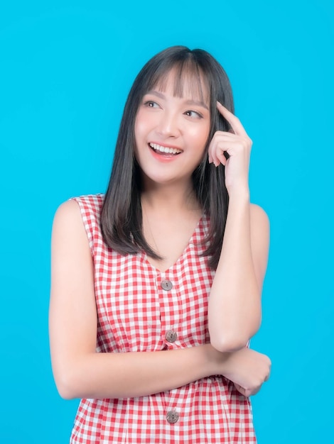 Young beautiful Asian woman pointed a finger to her head and smiled isolated on green background She think that she is coming up with new plans to get her work done thinking woman concept